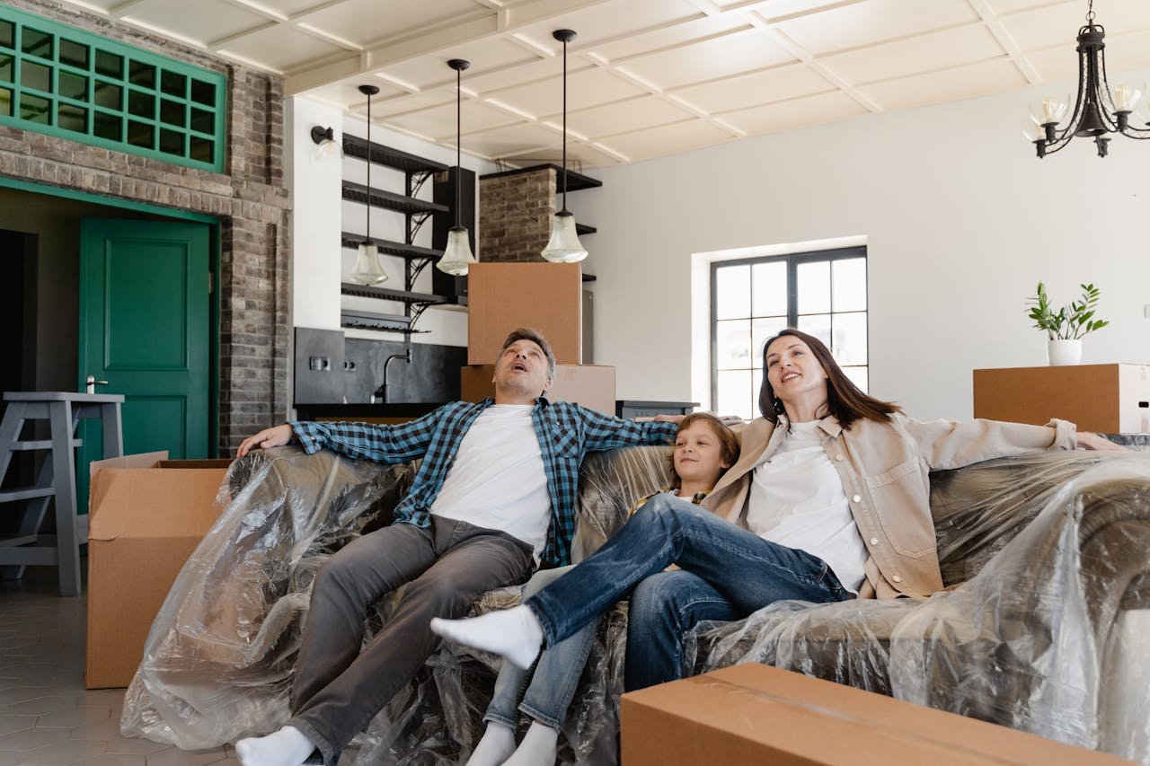 Contact A family sits on a couch in a new home surrounded by moving boxes.